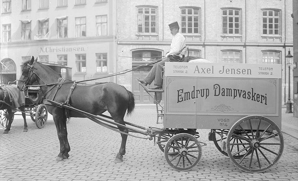 Lukket vogn til indsamling og udbringning af vasketøj fra Emdrup Dampvaskeri v. Axel Jensen. Vognen er forspændt én hest, der går med bringeseletøj.