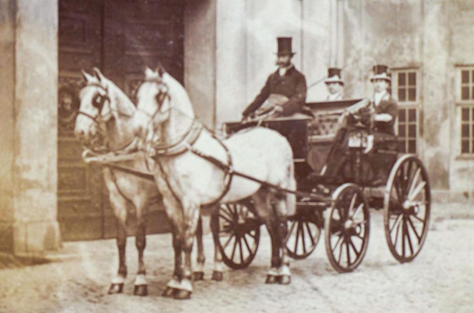 Christian 9. kører et skimlet 2-spand med kumteseler forspændt en phaeton. Foto: Georg E. Hansen, før 1891, Det Kgl. Biblioteks billedsamling.