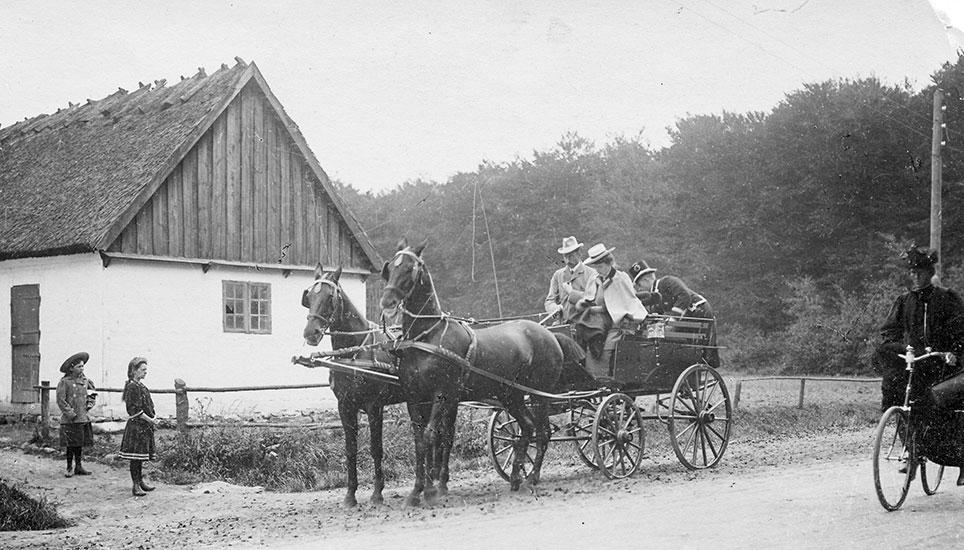 Kronprins Christian (10.) og kronprinsesse Alexandrine holder i 1899 med 2-spand og jagtvogn ved skovløberhuset, Kongevejskrydset ved Geels Skov. En biløber står bagpå vognen. Foto: Historisk Arkiv for Rudersdal Kommune