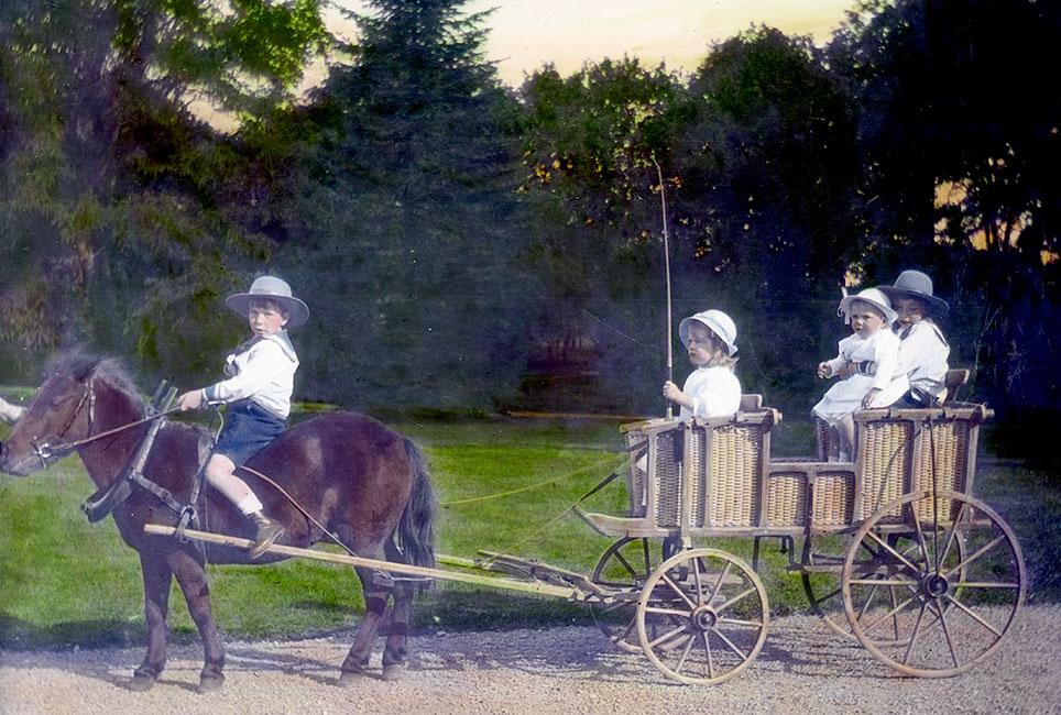 Prinsesse Ingrid og hendes brødre, prinserne Gustaf Adolf Sigvard, Bertil og Sigvard Bernadotte, kører med pony og vogn i parken ved Sofiero, Sverige, ca. 1914. Foto: håndkolorerede dias. © Kronprinsesse Margareta af Sverige, Dronning Ingrids Samling, Den kongelige Fotografisamling.