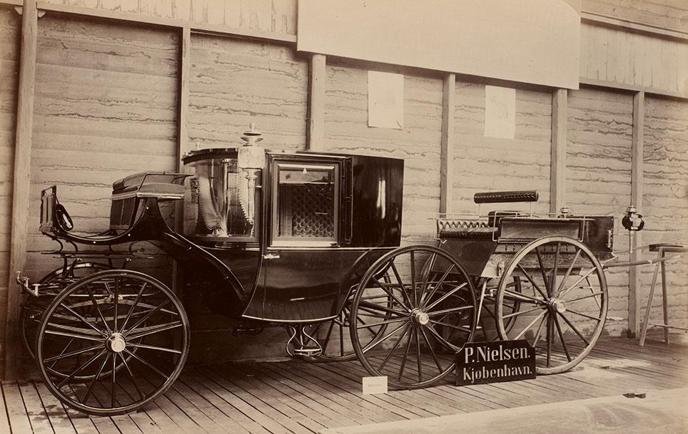 Clarence eller 3/4 coupé og 2-hjulet dogcart fra vognfabrikant P. Nielsen i København. Vognene er her udstillet ved "Den Nordiske Industri-, Landbrugs- og Kunstudstilling i Kjøbenhavn" 1888. Bemærk den spejlblanke lakering. Foto: DTU's bibliotek. 