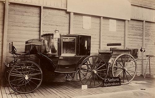 Clarence eller 3/4 coupé og 2-hjulet dogcart fra vognfabrikant P. Nielsen i København. Vognene er her udstillet ved "Den Nordiske Industri-, Landbrugs- og Kunstudstilling i Kjøbenhavn" 1888. Foto: DTU's bibliotek.